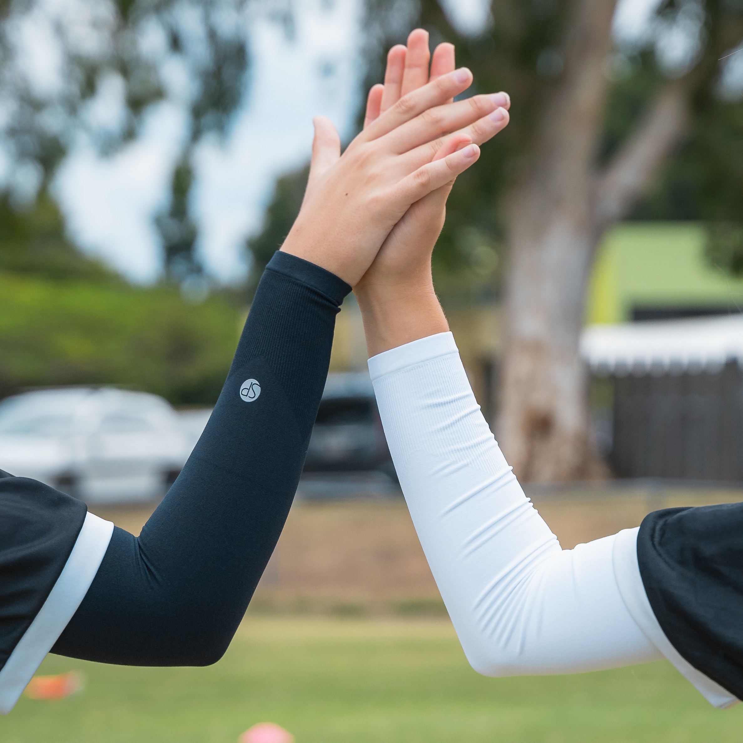 Image of two people wearing SParms sun sleeves and high-fiving.